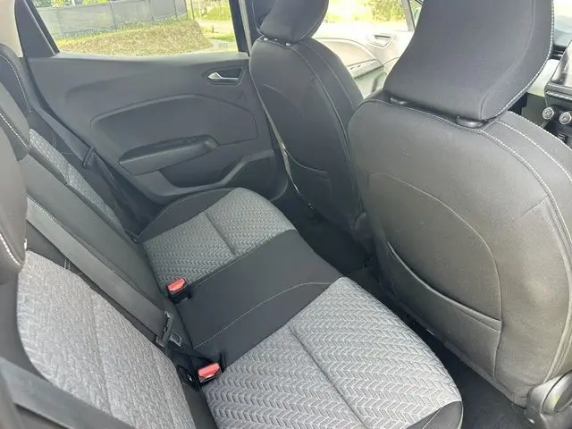 Vue intérieure arrière côté gauche de la Renault Clio 1.0 TCE Evolution 2022, sièges tissu gris et noir avec ceinture de sécurité rouge.