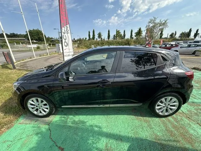 Profil côté gauche d'une Renault Clio 1.0 TCE Evolution noire 2022, garée en extérieur sur un sol vert.