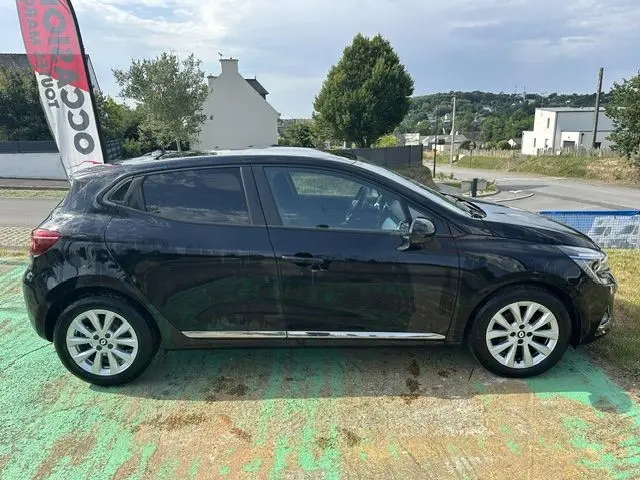 Profil droit d'une Renault Clio 1.0 TCE Evolution noire de 2022, garée en extérieur sur un sol coloré.