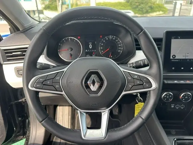 Volant noir de Renault Clio 1.0 TCE Evolution 2022, avec commandes intégrées et tableau de bord digital en arrière-plan.