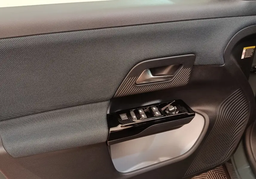 Gros plan sur la porte intérieure côté conducteur de la Citroën C5 hybride 2026, avec commandes de vitres et poignée noire.