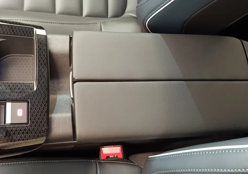 Gros plan sur l'accoudoir central noir et la console centrale avec bouton frein électrique dans l'habitacle d'une Citroën C5.