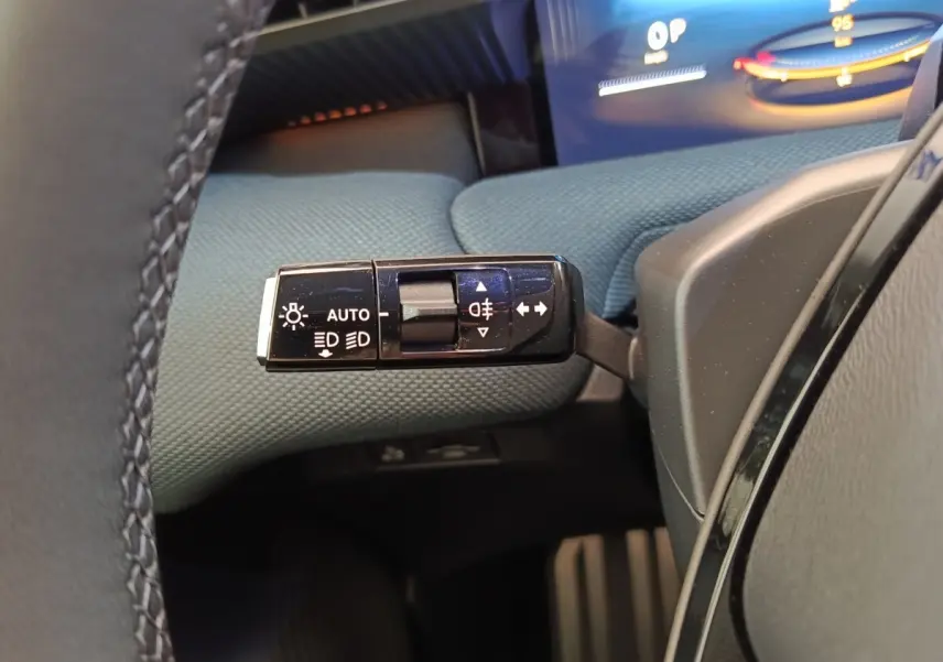 Gros plan sur la commande des feux et clignotants dans l’habitacle du Citroën C5 Hybride 2026, tissu bleu visible.