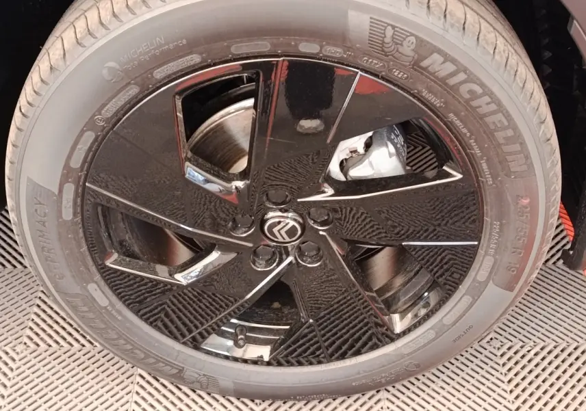 Gros plan sur la roue avant droite noire brillante d'une Citroën C5 Hybride 2026 avec logo Citroën au centre.