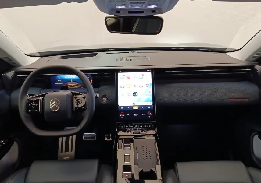 Vue intérieure avant du tableau de bord noir du Citroën C5 Hybride 2026 avec écran tactile vertical central lumineux.