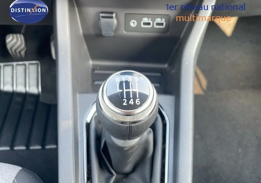Gros plan sur le levier de vitesses manuel 6 rapports de la Renault Clio noire, avec prises USB en arrière-plan.