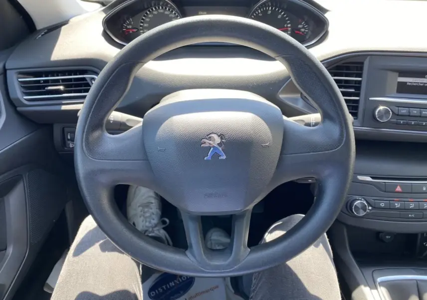 Vue intérieure centrée sur le volant noir de la Peugeot 308 SW 2017 avec tableau de bord et console centrale visibles.