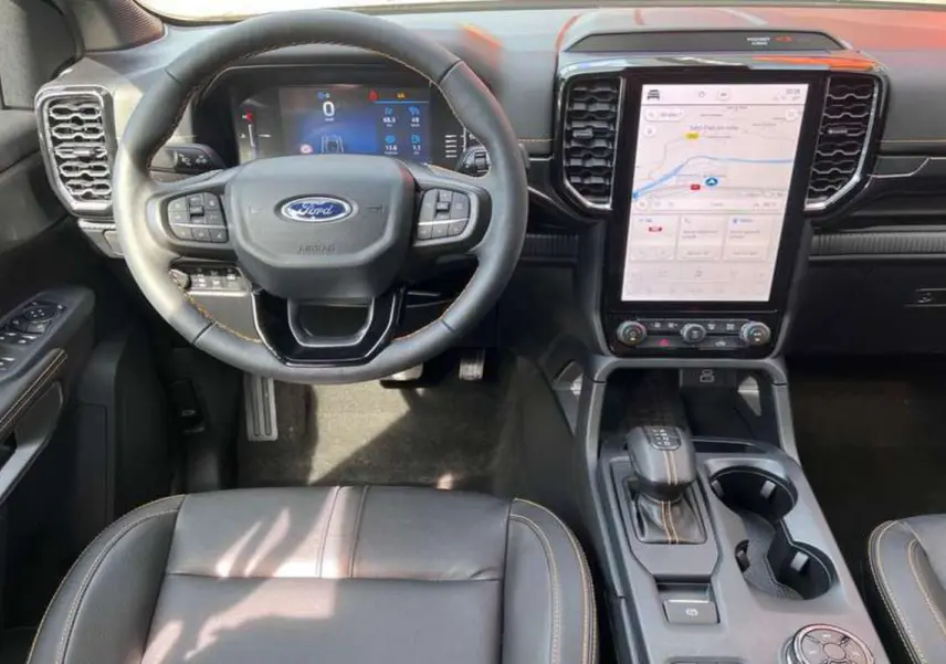 Intérieur du Ford Ranger Wildtrak 2025 vu de face, avec volant cuir, écran tactile vertical et console centrale noire.