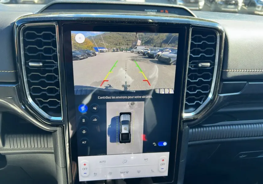 Vue rapprochée de l'écran central tactile du Ford Ranger 2025 bleu lightning montrant la caméra de recul et les aides au stationnement.
