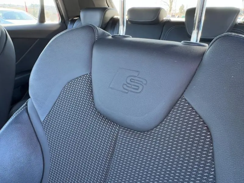 Gros plan sur le siège avant sport noir avec logo S embossé, intérieur de l'Audi Q2 30 TDI 2024.