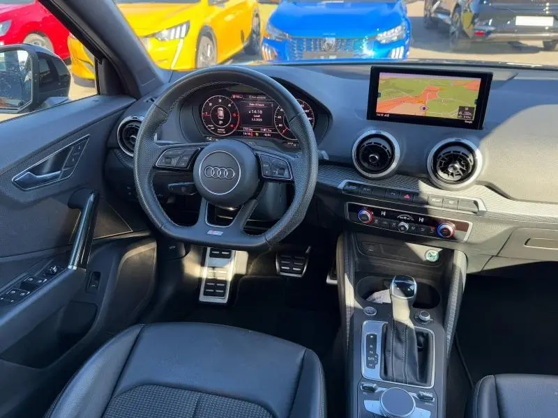 Vue intérieure de l'Audi Q2 30 TDI 2024, tableau de bord noir avec écran GPS et volant multifonction cuir.