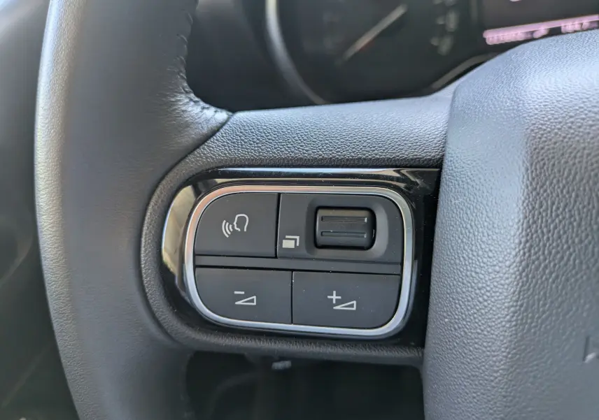 Gros plan sur la commande de régulateur de vitesse au volant d'une Citroën C3 Aircross 2024 gris Artense.