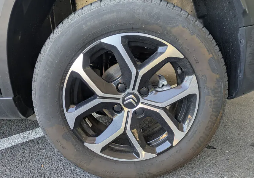 Gros plan sur la jante alliage 16 pouces et pneu Bridgestone du côté avant droit d'une Citroën C3 Aircross gris Artense.