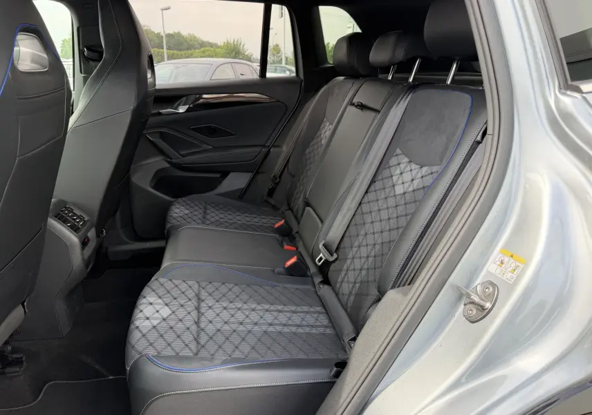 Vue côté droit de l'habitacle arrière du Volkswagen Tiguan gris, avec sièges en tissu et cuir noir à surpiqûres bleues.