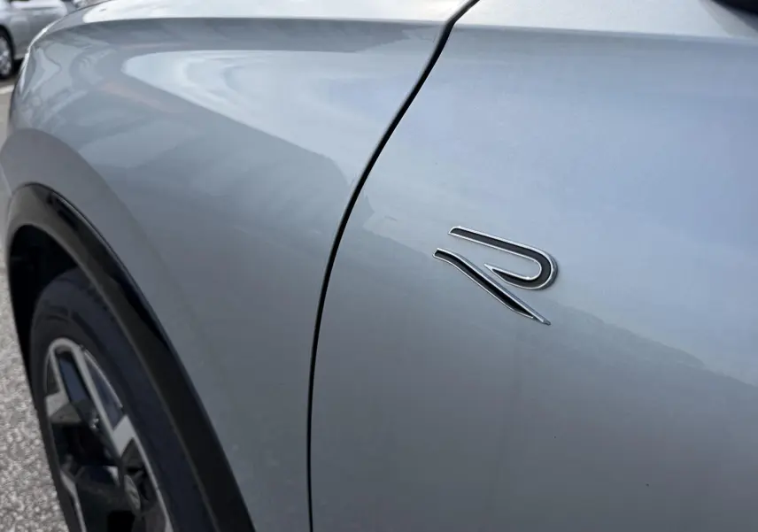 Détail du logo R sur l'aile avant gauche d'un Volkswagen Tiguan gris métallisé, avec jante noire visible.