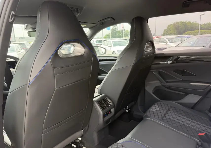 Vue intérieure arrière du Volkswagen Tiguan 2025, sièges sport noirs avec surpiqûres bleues et détails modernes.
