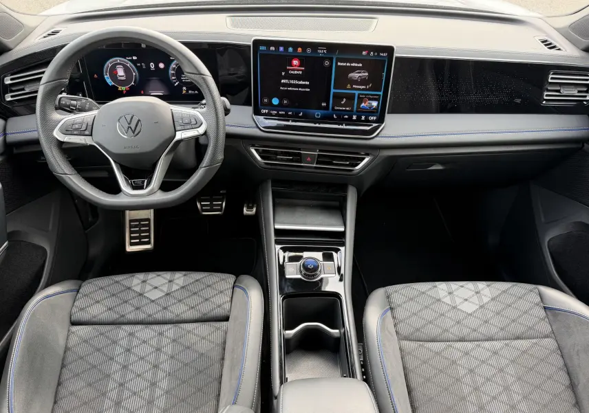 Vue intérieure avant du Volkswagen Tiguan 2025, tableau de bord numérique et sièges sport gris à surpiqûres bleues.
