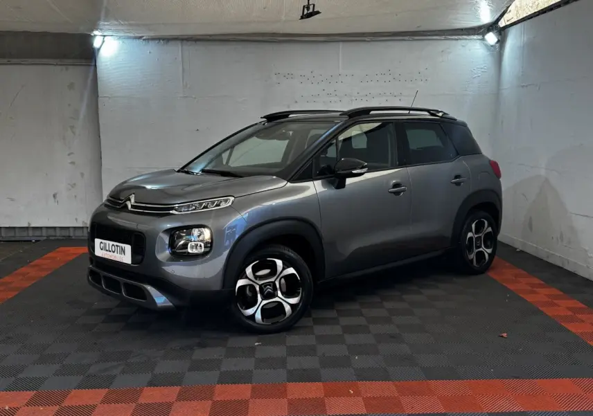 Citroën C3 PureTech 110 gris foncé en 3/4 avant droit, avec toit noir et jantes distinctives en alliage.