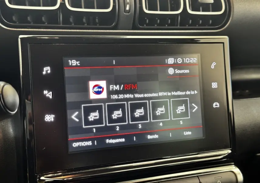 Écran tactile central de la Citroën C3 gris foncé, affichant la radio FM avec commandes tactiles et aérateurs supérieurs.