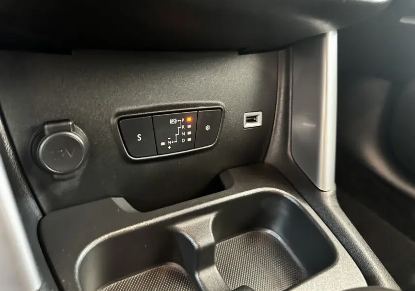Détail intérieur de la console centrale de la Citroën C3 gris foncé, avec commandes de boîte automatique et prise 12V visible.