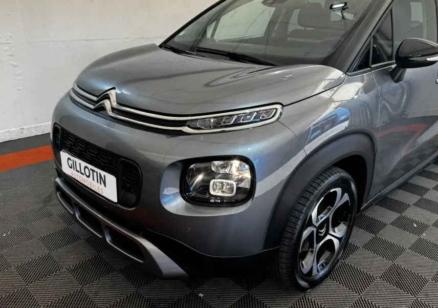 Vue 3/4 avant droit d'une Citroën C3 PureTech 110 gris foncé avec phares LED et jantes bicolores distinctives.