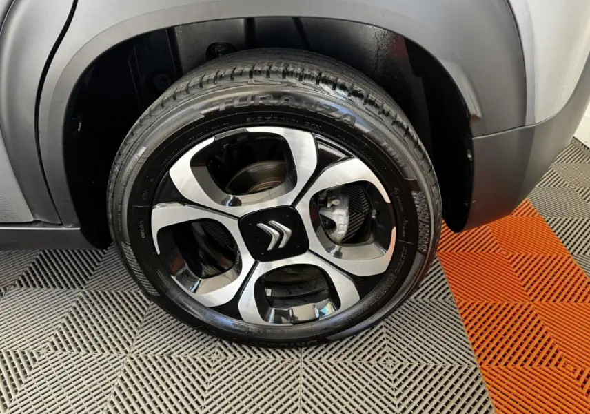 Gros plan sur la roue avant droite d'une Citroën C3 gris foncé avec jante alliage noire et argentée au design distinctif.
