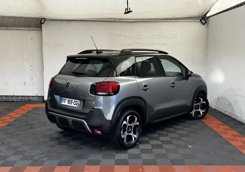Vue 3/4 arrière droite d'une Citroën C3 gris foncé avec toit noir et jantes distinctives en alliage.