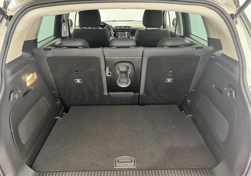 Vue depuis le coffre d'une Citroën C3 gris foncé, montrant la banquette arrière et l'écran tactile du tableau de bord.