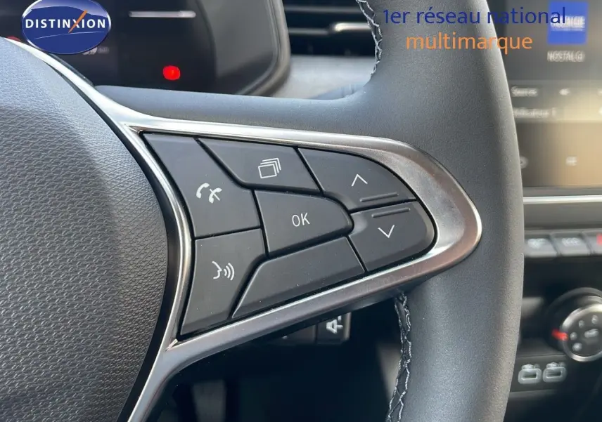 Gros plan sur les commandes multifonctions au volant d'une Renault Clio 1.5 DCI noire, intérieur moderne avec écran tactile visible.