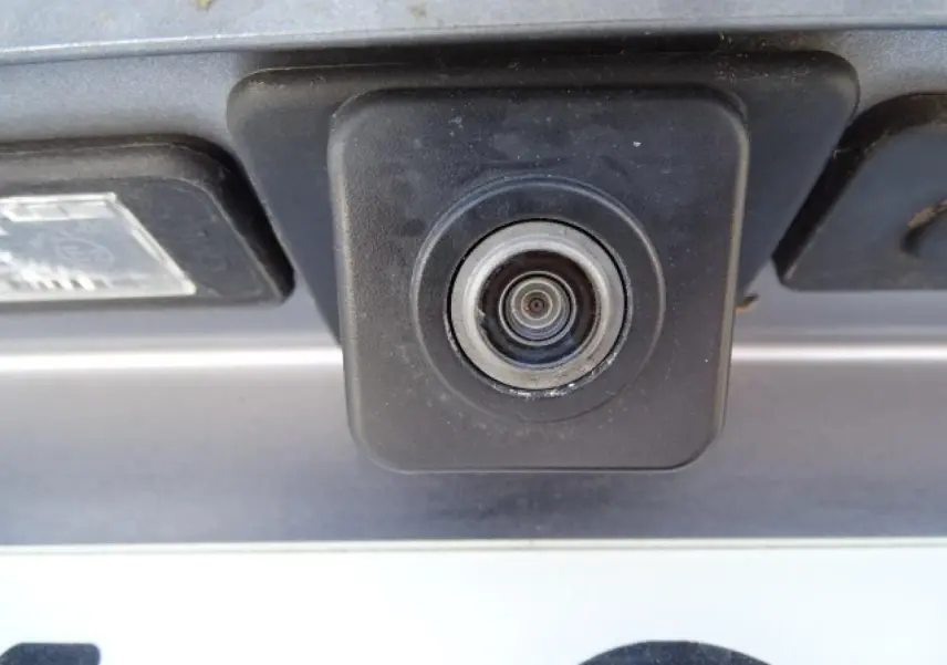 Gros plan sur la caméra de recul noire intégrée au hayon arrière du Peugeot 3008 gris Artense de 2017.