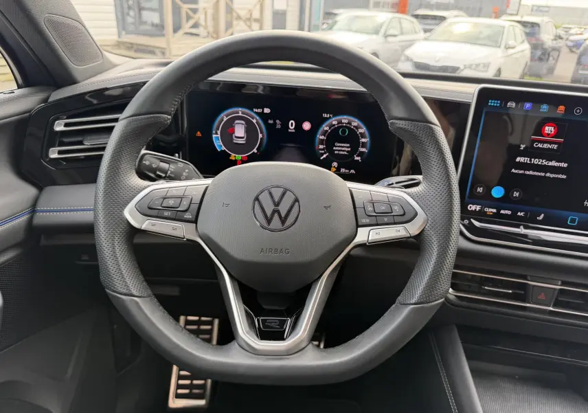 Vue intérieure centrée sur le volant cuir multifonction du Volkswagen Tiguan 2025 avec tableau de bord digital et écran tactile.