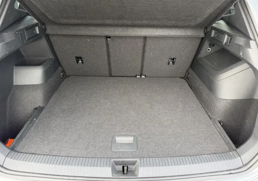 Coffre ouvert vu de l'arrière du Volkswagen Tiguan gris, montrant un espace de chargement propre et bien agencé.
