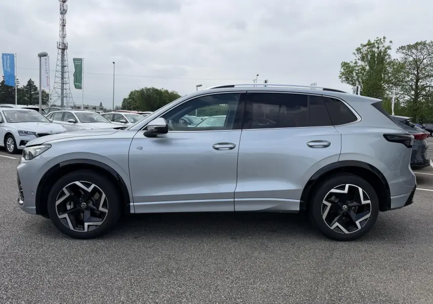 Vue de profil côté gauche d'un Volkswagen Tiguan gris métallisé avec jantes alliage 19 pouces et vitres teintées.