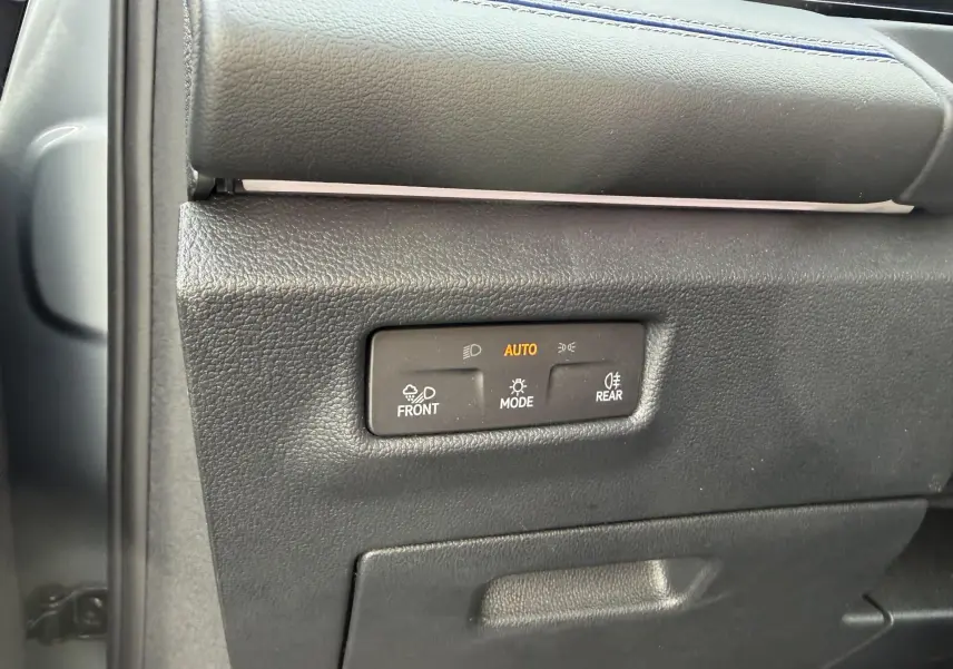 Gros plan sur les commandes d’éclairage automatiques du tableau de bord du Volkswagen Tiguan gris, côté conducteur.