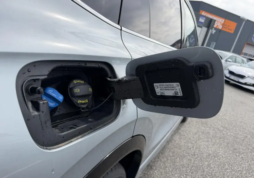 Vue rapprochée de la trappe à carburant côté gauche du Volkswagen Tiguan gris métallisé 2025 avec bouchon diesel ouvert.
