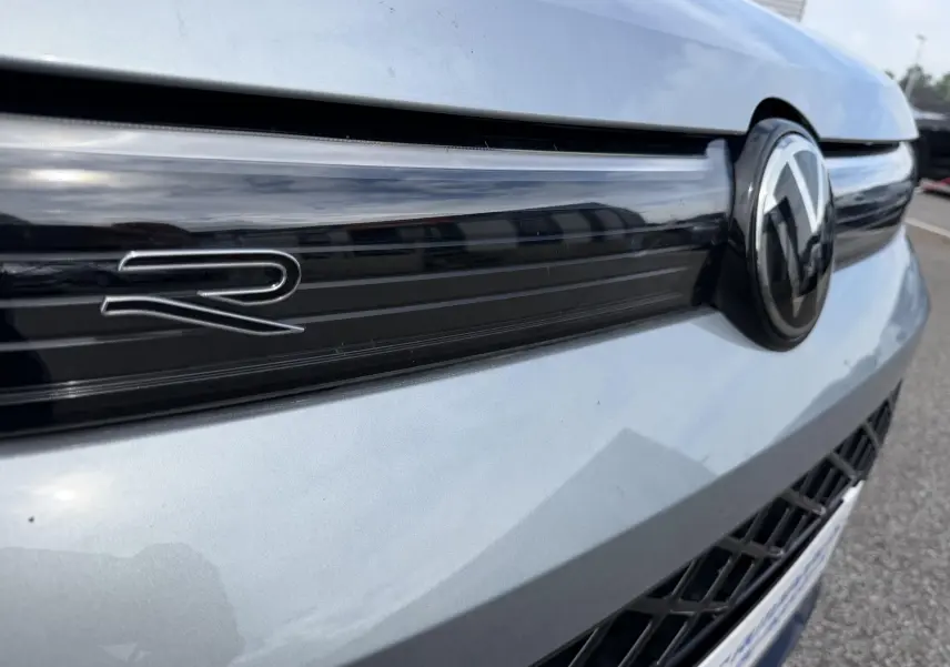 Gros plan sur la calandre avant grise d’un Volkswagen Tiguan avec logo VW et sigle R en relief noir brillant.
