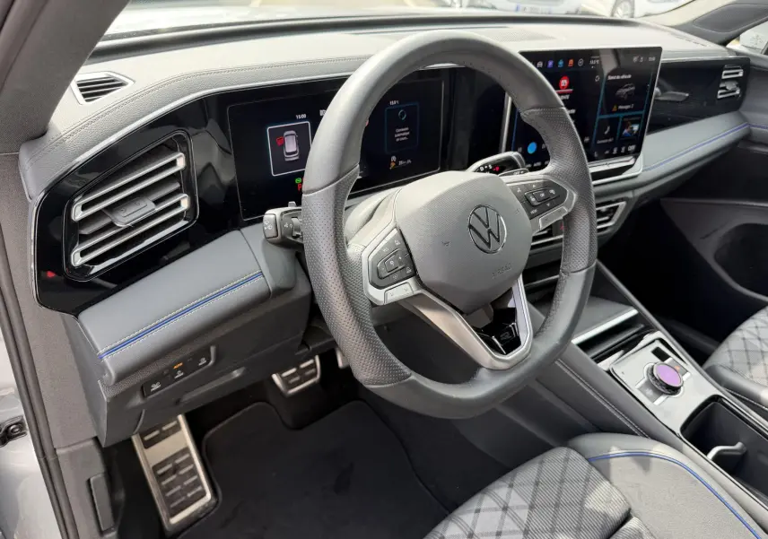 Vue intérieure côté conducteur du Volkswagen Tiguan gris 2025, volant cuir multifonction et tableau de bord digital.