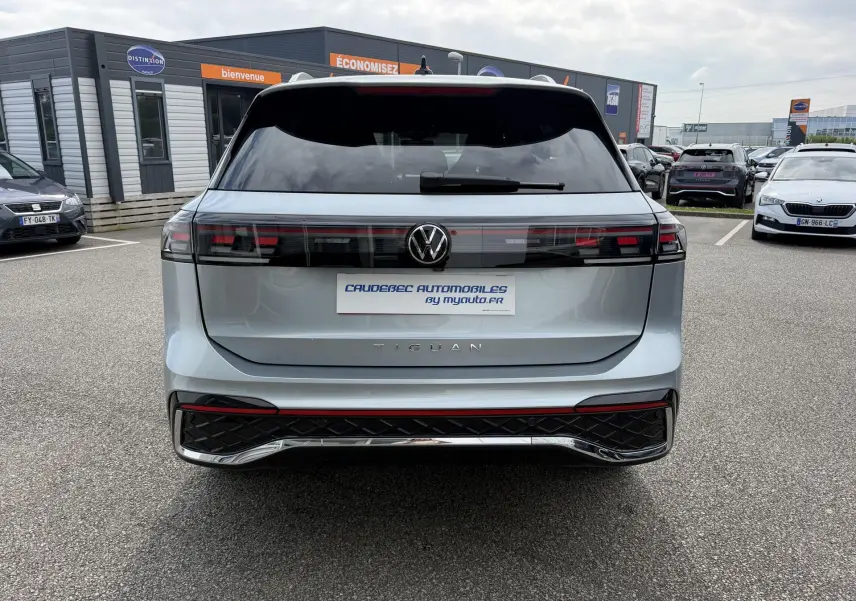 Vue arrière du Volkswagen Tiguan gris métallisé 2025 avec feux arrière LED et logo VW centré sur un parking.