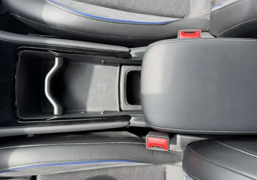 Vue plongeante sur la console centrale noire et les sièges gris avec surpiqûres bleues du Volkswagen Tiguan 2025.