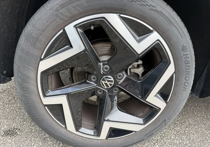 Gros plan sur la jante alliage 19 pouces bicolore noir et argent du Volkswagen Tiguan gris, avec logo VW central.