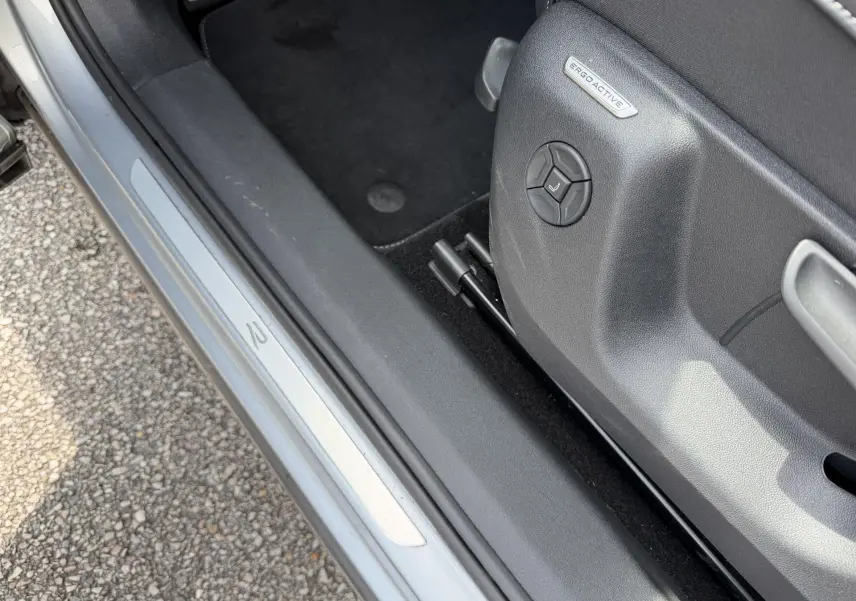 Gros plan sur le seuil de porte côté gauche du Volkswagen Tiguan gris avec réglage siège ErgoActive visible.