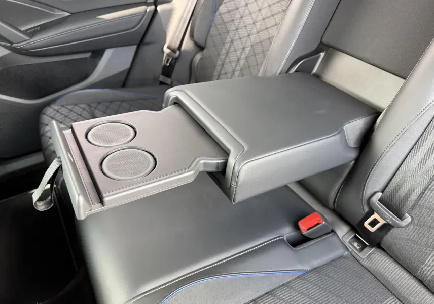 Vue rapprochée de l'accoudoir central arrière déployé avec porte-gobelets sur la banquette arrière grise du Volkswagen Tiguan 2025.