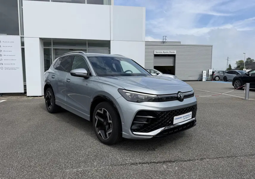 Volkswagen Tiguan gris métallisé en 3/4 avant droit, avec calandre noire et jantes alliage distinctives.