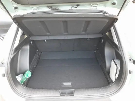 Vue du coffre ouvert d'une Hyundai Kona 2024 Mirage Green, montrant l'espace de rangement intérieur vide et propre.