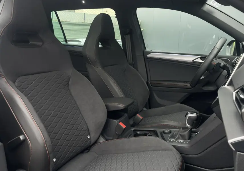 Intérieur du SEAT Tarraco 1.4 e-Hybrid 2024, vue côté conducteur, sièges sport noirs avec surpiqûres orange.