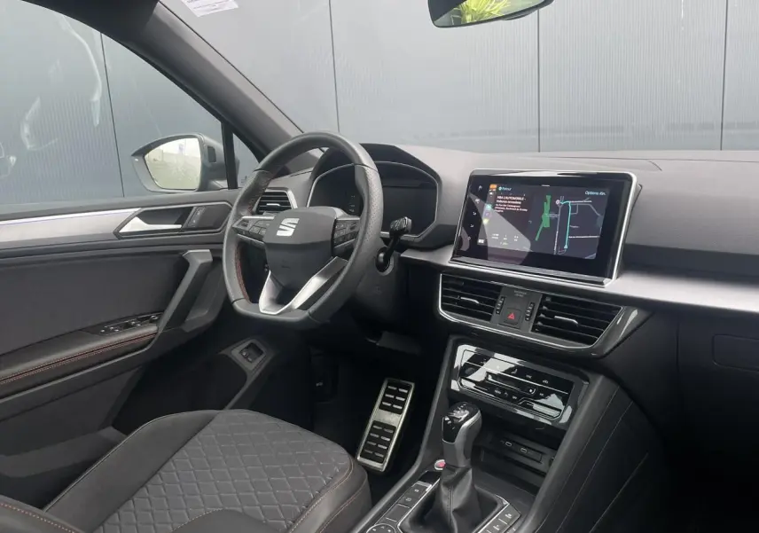 Intérieur côté conducteur du SEAT Tarraco 2024, volant cuir multifonction et écran tactile de navigation visible.