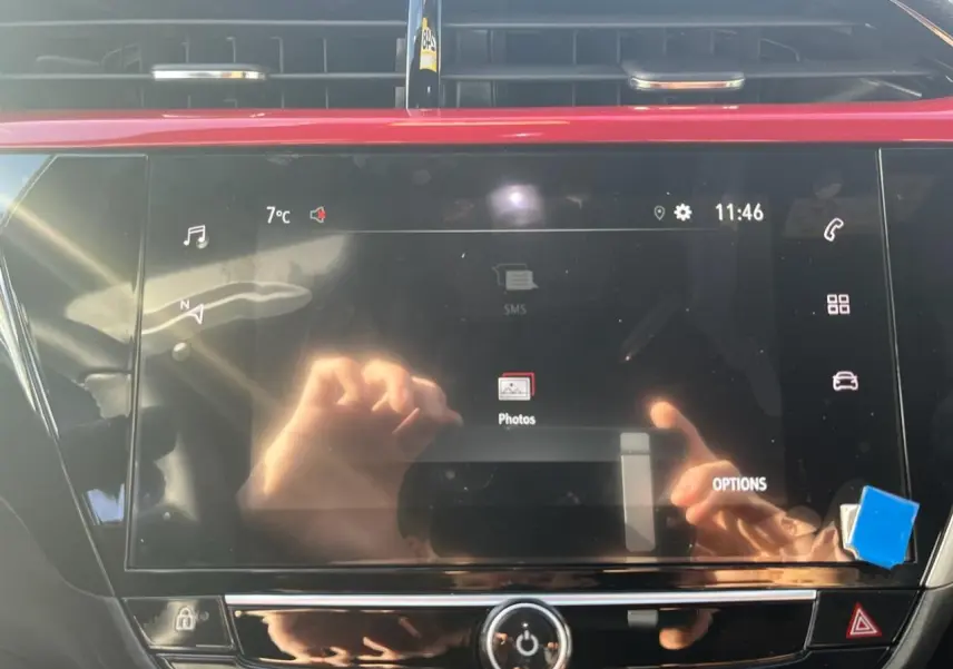 Écran tactile couleur 7 pouces de l'Opel Corsa GS Line 2022 avec reflet de mains et tableau de bord noir.