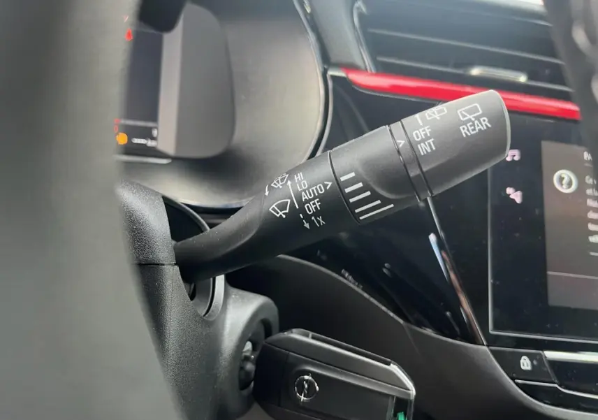 Gros plan sur la commande d'essuie-glace côté droit du volant d'une Opel Corsa GS Line noire avec tableau de bord et écran tactile.