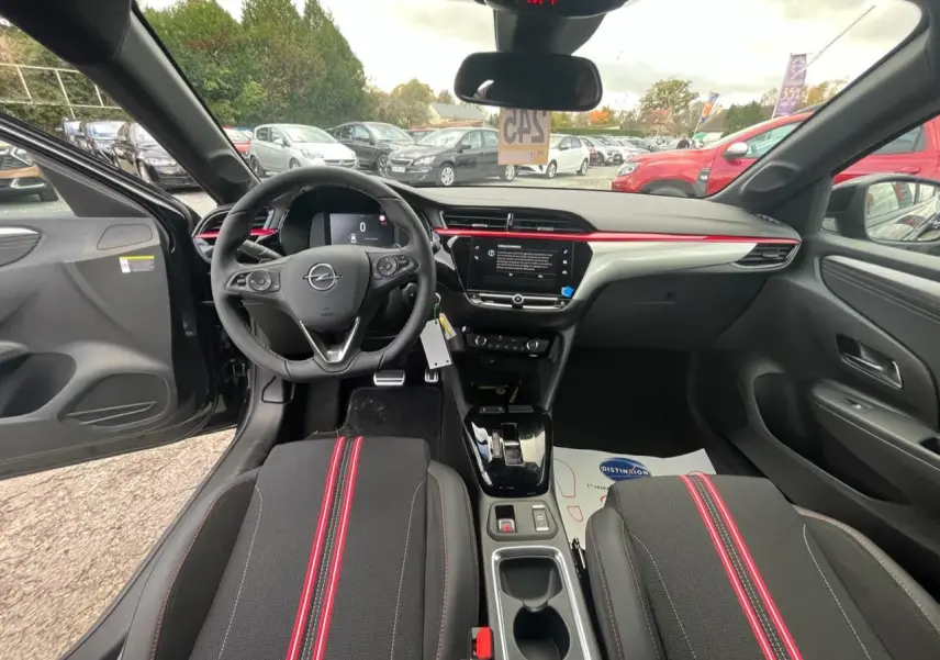 Vue intérieure avant de l'Opel Corsa GS Line 2022 noire, avec volant multifonction et bande rouge décorative sur la planche de bord.