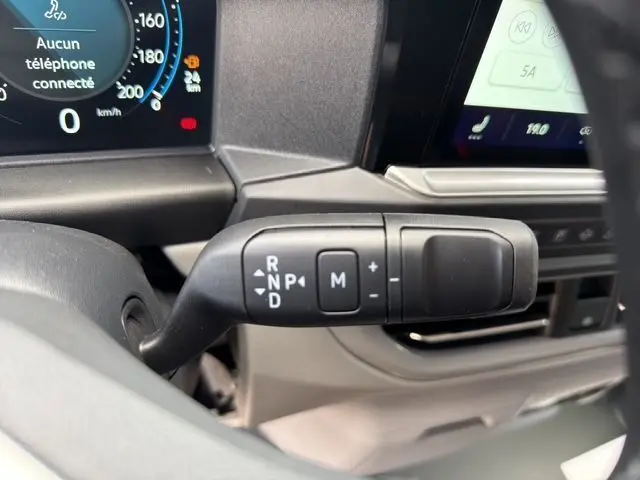 Gros plan sur la commande de boîte automatique noire du Volkswagen Transporter ProCab 2026, tableau de bord partiellement visible.